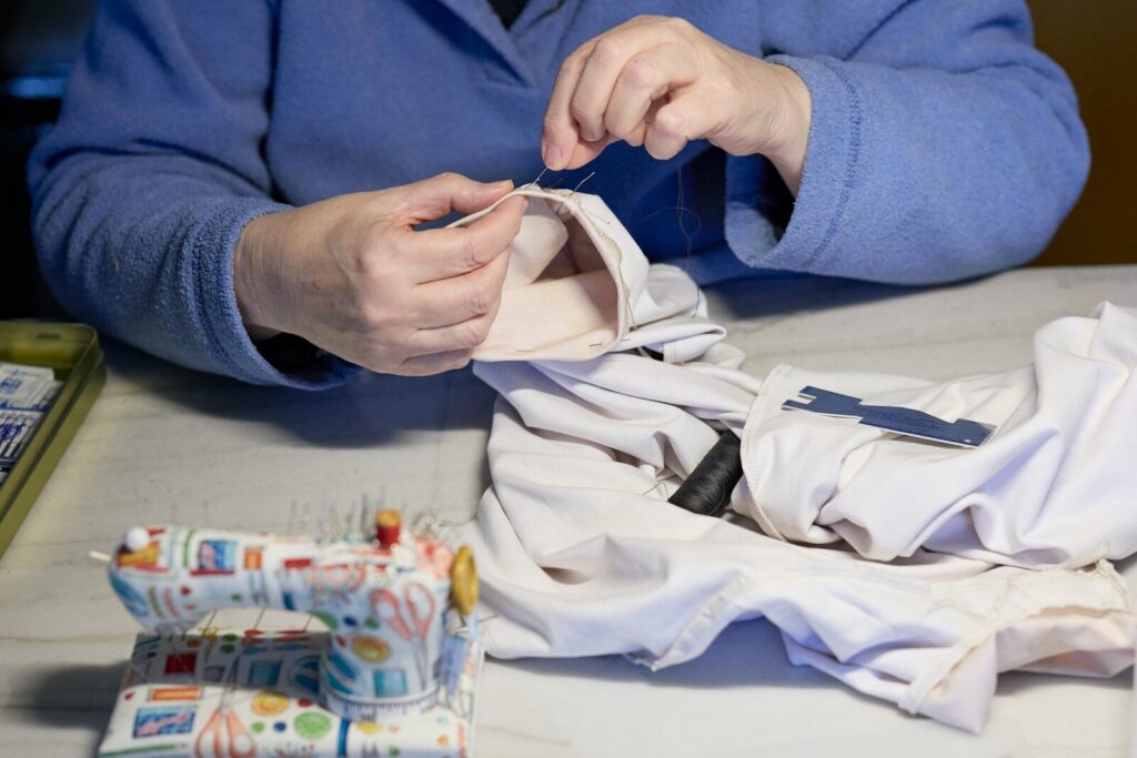 A person sewing fabric with a needle and thread.